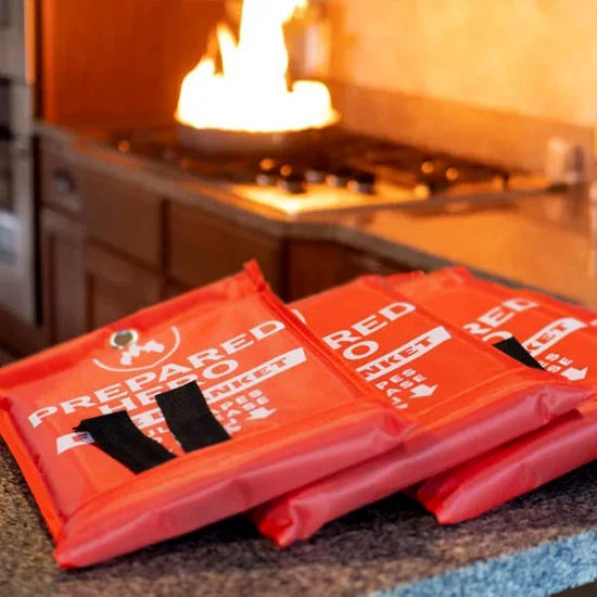 Three Prepared Hero Fire Blanket pouches on kitchen counter with stovetop fire in background