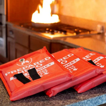 Three Prepared Hero Fire Blanket pouches on kitchen counter with stovetop fire in background